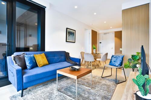 a living room with a blue couch and a table at Box Hill Central Sky One Apartment in Box Hill