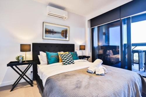 a bedroom with a large bed with a large window at Box Hill Central Sky One Apartment in Box Hill