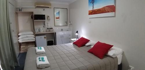 1 dormitorio con 1 cama con almohadas rojas y blancas en Taree Country Motel en Taree