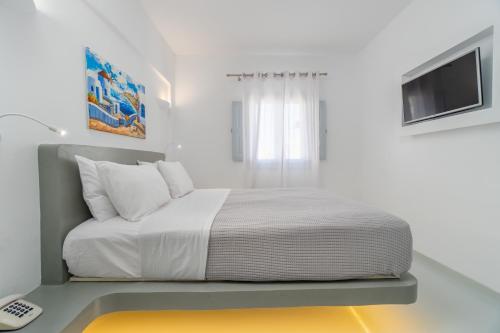 a white bedroom with a bed and a television at Central Fira Suites in Fira