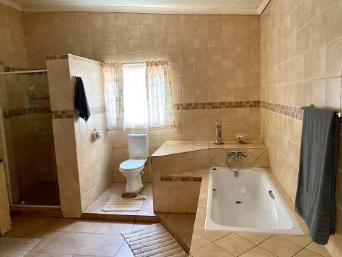 a bathroom with a tub and a toilet and a sink at La Bella B&B Under The Fig Tree in Bela-Bela