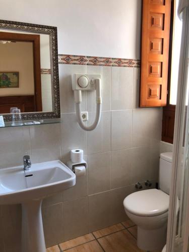 a bathroom with a sink and a toilet and a mirror at Hostal Loreto in Denia