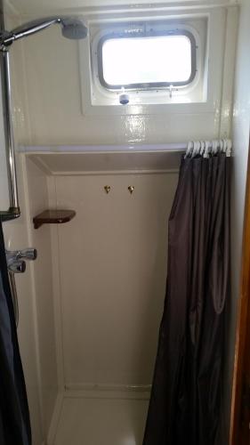 a bathroom with a window and a shower curtain at Tjalkjacht Pelikaan Lemmer in Lemmer