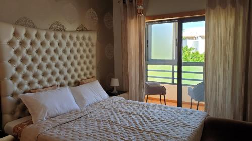 ein Schlafzimmer mit einem großen Bett und einem großen Fenster in der Unterkunft Luxury city Villa Olivia 10 - 15 min to the Beach Oura, private swimming pool in Albufeira