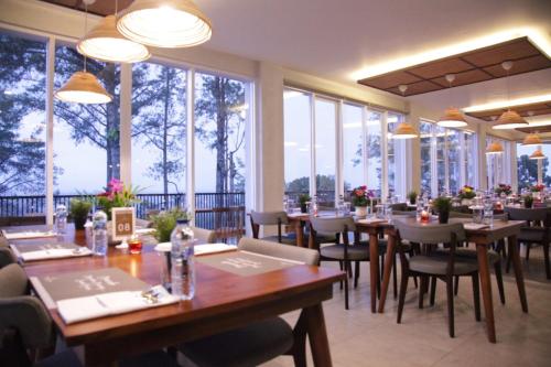 武吉丁宜的住宿－The Balcone Suites & Resort Powered by Archipelago，餐厅设有桌椅和大窗户。