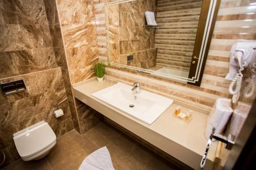 a bathroom with a sink and a toilet and a mirror at HOTEL PALAIS ROYAL in Sfax