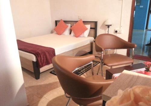 una camera d'albergo con un letto e sedie di Mahoya a Mawanella