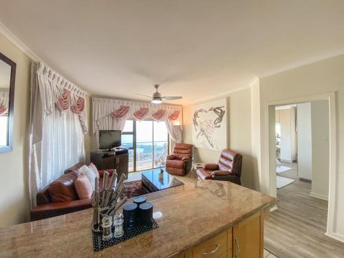 a kitchen and living room with a couch and a table at Bar-t-nique Guest House in Mossel Bay