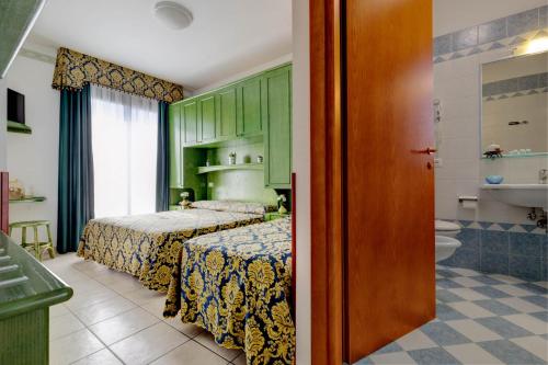 ein Schlafzimmer mit 2 Betten und ein Badezimmer in der Unterkunft Hotel Garni San Carlo in Lido di Jesolo