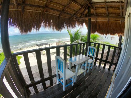 uma mesa e cadeiras num deque com praia em Casa Kayab em Puerto Morelos