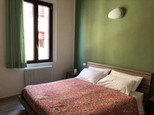 a bedroom with a bed with a red blanket and a window at Triquetra in Ferrara