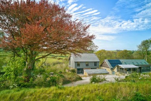 a house and a barn in a field with a tree at Glamping Yurts near Newquay in Newquay