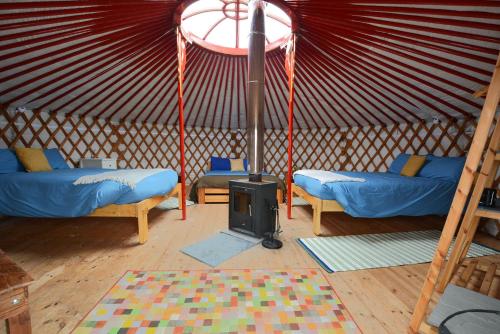 a room with two beds and a stove in a yurt at Glamping Yurts near Newquay in Newquay