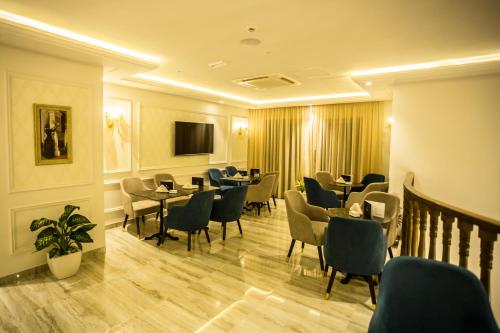 a waiting room with tables and chairs and a tv at HOTEL PALAIS ROYAL in Sfax