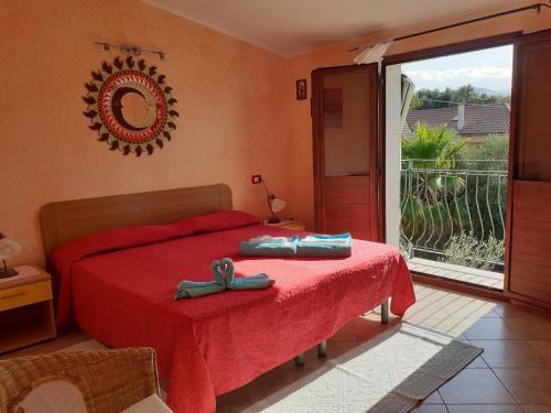 a bedroom with a bed with a red spread and a window at B&B Sa Funtana in Cardedu