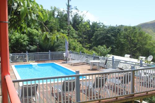 eine Terrasse mit Stühlen und einen Pool auf dem Balkon in der Unterkunft Oasis de Grande Anse in Deshaies