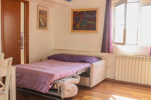ein Schlafzimmer mit einem Bett mit violetter Bettwäsche und einem Fenster in der Unterkunft Attico con terrazza unico in Cagliari