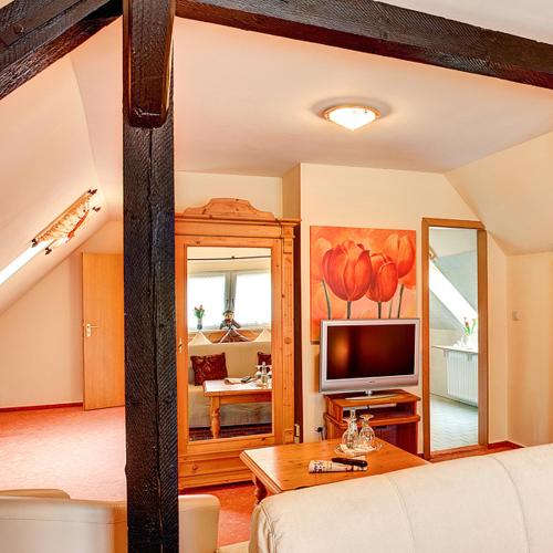 a living room with a couch and a television at Stadthotel Detmold in Detmold