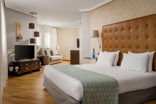 a bedroom with a large bed and a living room at Exe Getafe in Getafe