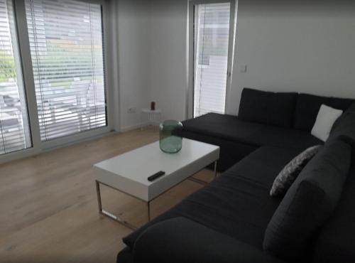 ein Wohnzimmer mit einem schwarzen Sofa und einem weißen Couchtisch in der Unterkunft Glanzvoller - Deine Auszeit in Markdorf