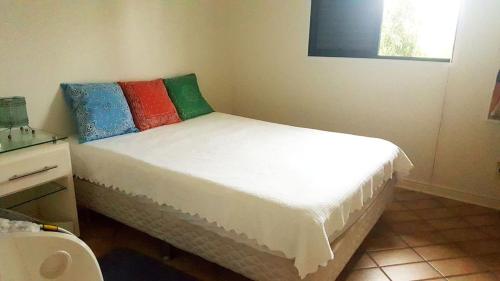a bedroom with a bed with colorful pillows on it at Riviera São Lourenço Acqua in Bertioga