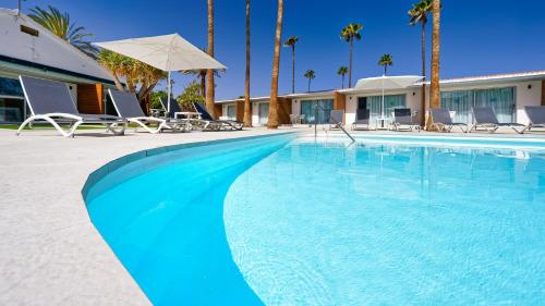 a large swimming pool with chairs and palm trees at Sanom Beach Resort Only Adults in Playa del Ingles