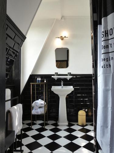 La salle de bains est pourvue d'un lavabo et d'un sol en damier noir et blanc. dans l'établissement Chateau de Hiéville, à Hiéville