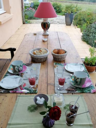 a wooden table with plates and bowls of food on it at La Tour du Bois Dormant in Plozévet