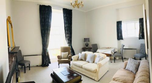 uma sala de estar com um sofá, cadeiras e uma mesa em Alexander House em Corsham