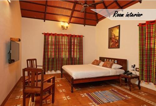 a bedroom with a bed and a chair in it at Marutham Village Resort in Mahabalipuram