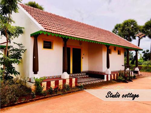 a small white house with a red roof at Marutham Village Resort in Mahabalipuram