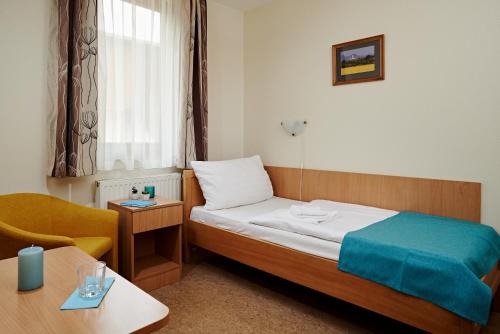 a hotel room with a bed and a chair and a table at Hotel Adalbert Szent György Ház in Esztergom