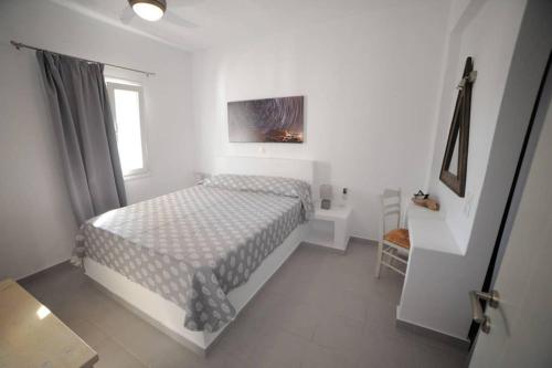 ein weißes Schlafzimmer mit einem Bett und einem Fenster in der Unterkunft Mariannas House in Naoussa