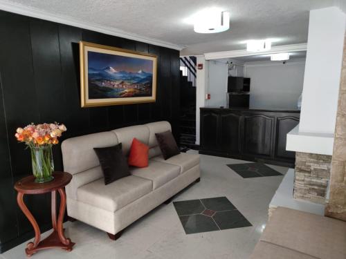 a living room with a couch and a vase of flowers at Val Hotel Santamaria Quito in Quito