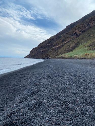 a rocky beach next to the ocean with a hill at Casa Schicciola in Stromboli