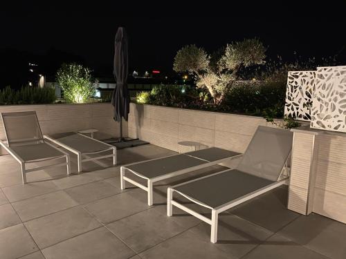three chairs and an umbrella on a patio at night at Lagrange Apart'Hôtel Antibes Olympie in Antibes