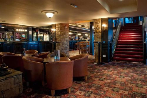 a bar with brown chairs and stairs in a building at Strangford Arms Hotel in Newtownards