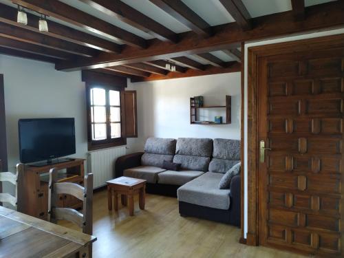 a living room with a couch and a tv at Apartamentos LLave de Santillana in Santillana del Mar