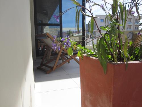a patio with a chair and flowers on a balcony at La Villa 126 Dakar in Dakar