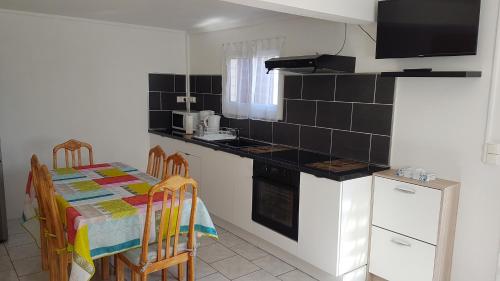uma cozinha com uma mesa e um fogão forno superior em Studio Climatisé Côte-sous-le-vent em Baillif