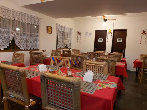 a restaurant with tables and chairs with red table cloth at Pousada Nayane in Barequeçaba