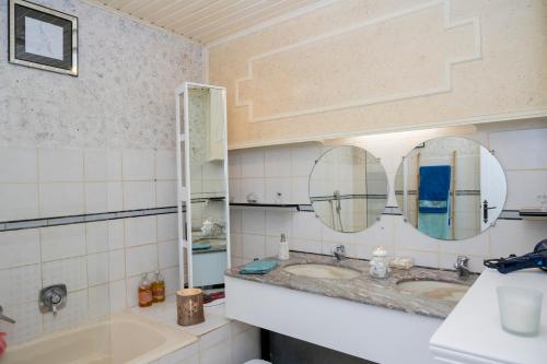 a bathroom with two sinks and two mirrors at Une HALTE Quelque PART in Cheminot