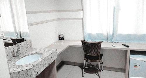 a bathroom with a sink and a chair in it at Hotel Ferrari in Lucas do Rio Verde