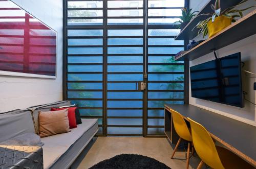 a living room with a couch and a desk and windows at Vila Pitanga Hosting in Sao Paulo