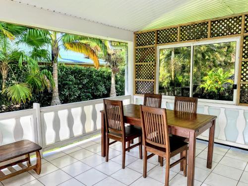 a dining room with a table and chairs and two windows at TAHITI - Fare Mitinui Surf Break in Mahina