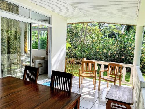 a screened in porch with a table and chairs at TAHITI - Fare Mitinui Surf Break in Mahina