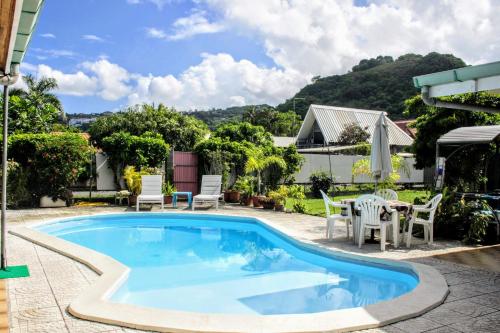 a swimming pool with chairs and a table on a patio at TAHITI - Sanny's Place Family Room & Poo in Punaauia