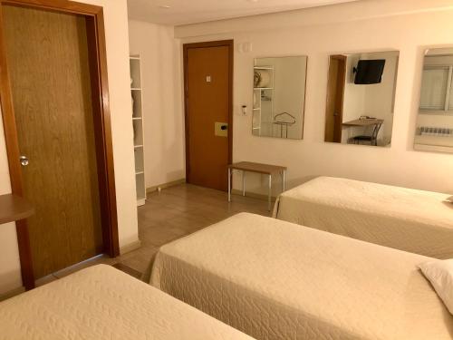 a hotel room with two beds and a table at Hotel Concatto in Farroupilha