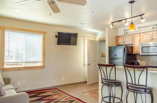a kitchen with two bar stools and a refrigerator at Cedar Wood Escape in Cedar City
