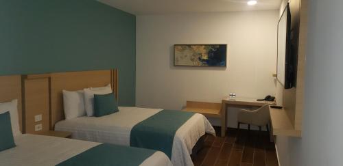 a hotel room with two beds and a desk at Hotel Plaza Sol Veracruz in Veracruz